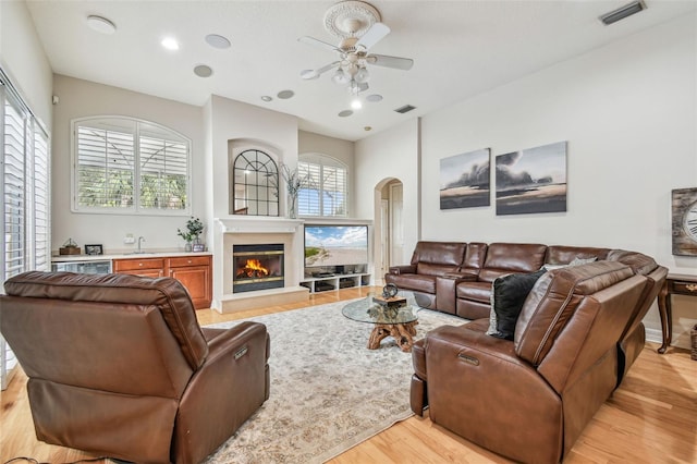 living room featuring ceiling fan, light wood-type flooring, and a wealth of natural light