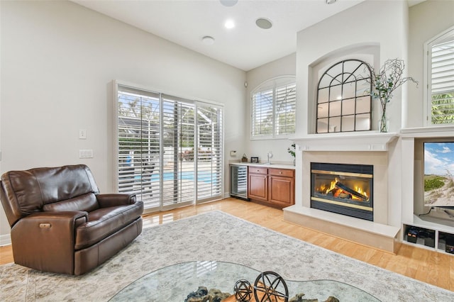 living area featuring a wealth of natural light, beverage cooler, and light wood-type flooring