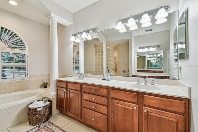 bathroom featuring tile patterned flooring, a relaxing tiled tub, vanity, and decorative columns