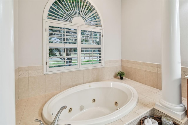 bathroom with a wealth of natural light, ornate columns, and a bath