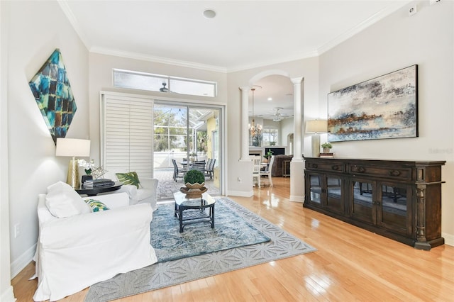 living area featuring hardwood / wood-style floors, crown molding, decorative columns, and baseboards