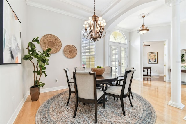 dining area featuring crown molding, baseboards, light wood-type flooring, french doors, and ornate columns