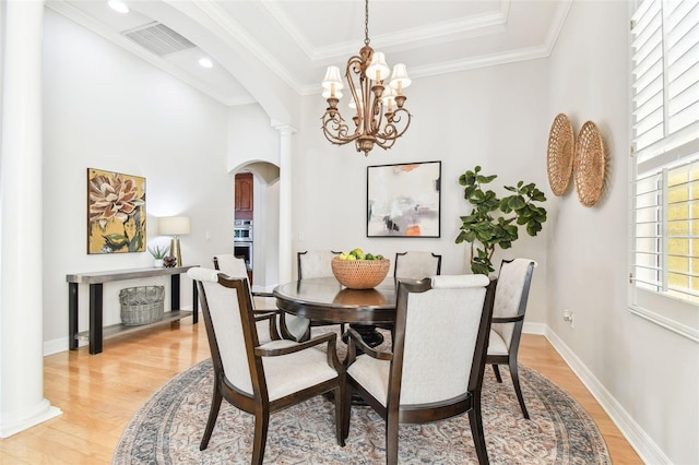 dining area featuring arched walkways, visible vents, light wood finished floors, and baseboards