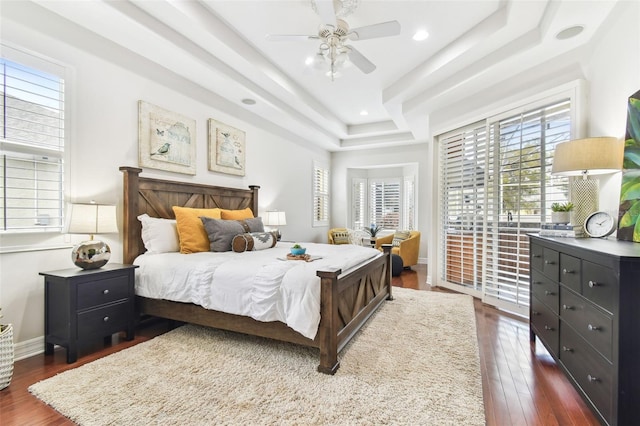 bedroom featuring baseboards, a tray ceiling, recessed lighting, a ceiling fan, and dark wood-style flooring