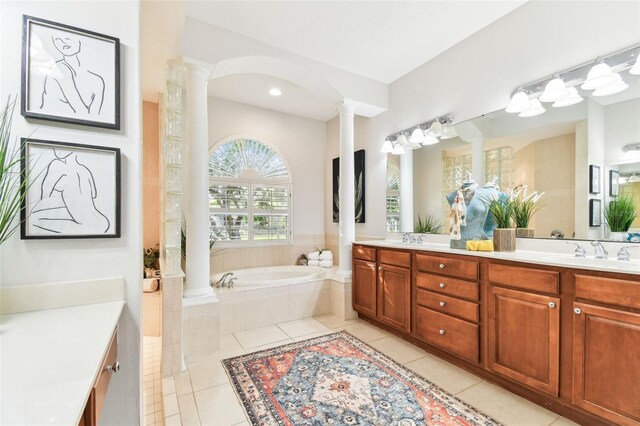 full bath featuring a garden tub, double vanity, decorative columns, a sink, and tile patterned floors