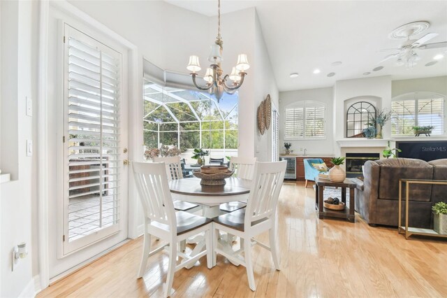 dining room featuring wood finished floors, recessed lighting, a sunroom, wine cooler, and a glass covered fireplace