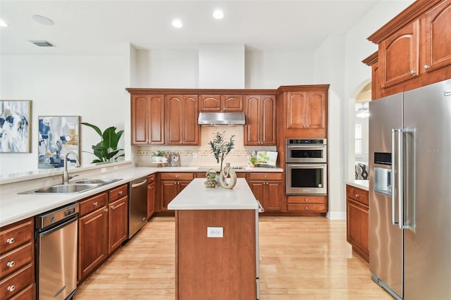 kitchen with visible vents, under cabinet range hood, light wood-type flooring, light countertops, and appliances with stainless steel finishes