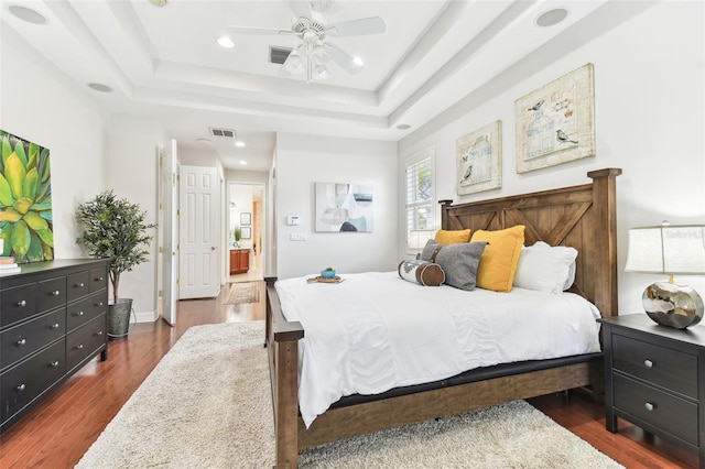 bedroom with visible vents, a raised ceiling, a ceiling fan, and dark wood-style flooring