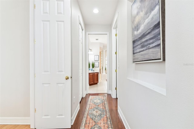 corridor featuring baseboards and wood finished floors