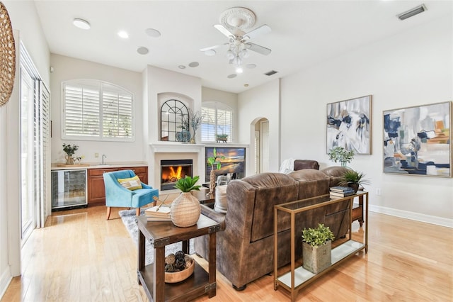 living room with wine cooler, visible vents, arched walkways, and a wealth of natural light