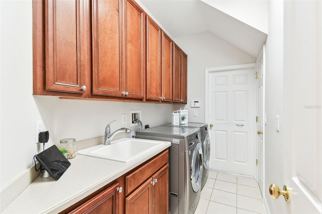 washroom featuring washing machine and clothes dryer, light tile patterned flooring, cabinet space, and a sink