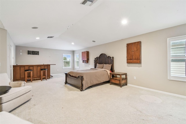 bedroom featuring a dry bar, baseboards, visible vents, and light carpet