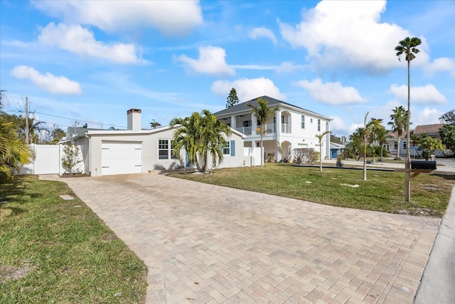 view of front facade with a balcony, a garage, and a front yard