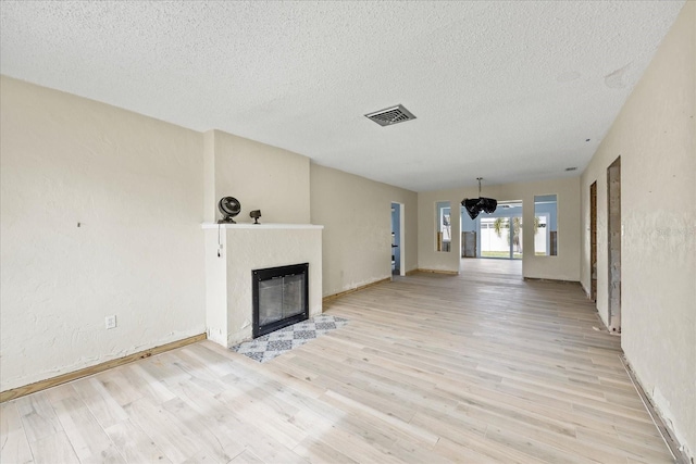 unfurnished living room with a textured ceiling, light hardwood / wood-style floors, and a fireplace