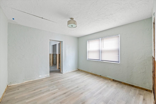 unfurnished room featuring a textured ceiling and light hardwood / wood-style floors