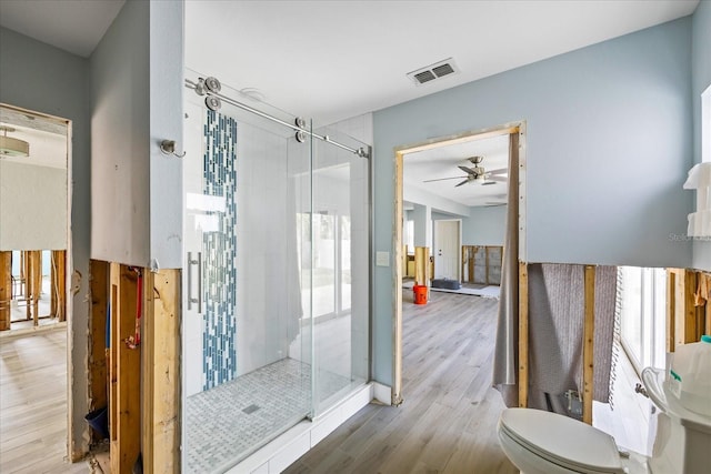 bathroom featuring toilet, ceiling fan, wood-type flooring, and walk in shower