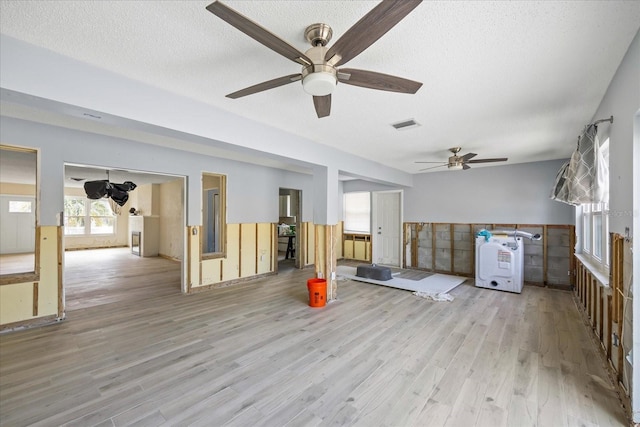 exercise room with light wood-type flooring, ceiling fan, and a textured ceiling