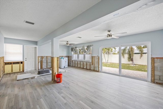 interior space featuring ceiling fan, a textured ceiling, light hardwood / wood-style flooring, and washer / dryer