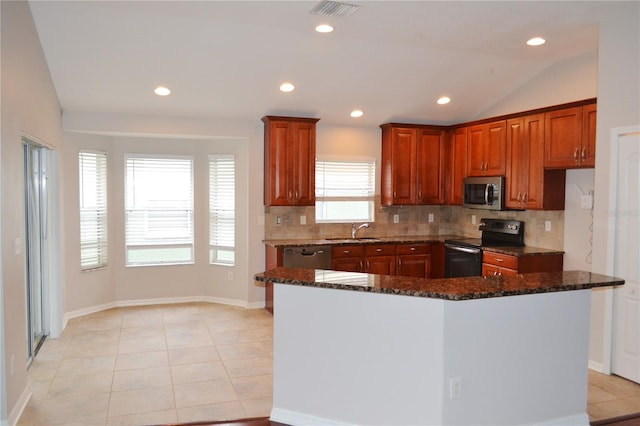 kitchen featuring vaulted ceiling, appliances with stainless steel finishes, dark stone counters, and a kitchen island