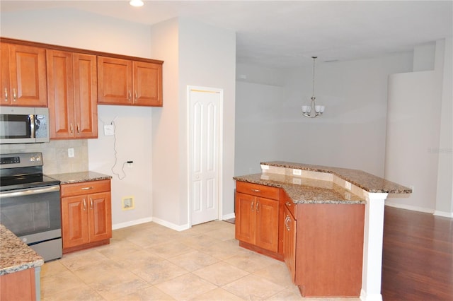 kitchen with appliances with stainless steel finishes, backsplash, hanging light fixtures, and light stone countertops