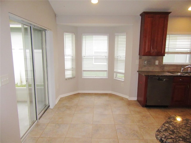 kitchen featuring backsplash, stainless steel dishwasher, sink, light tile patterned floors, and dark stone counters