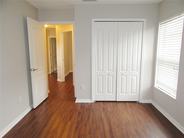 unfurnished bedroom with dark wood-type flooring and a closet