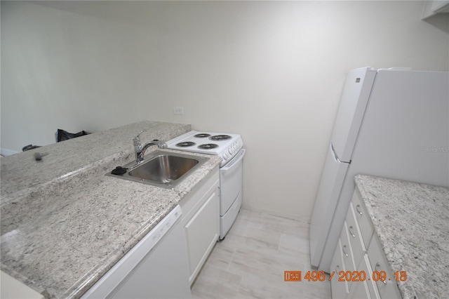 kitchen with white cabinetry, sink, light stone counters, and white appliances