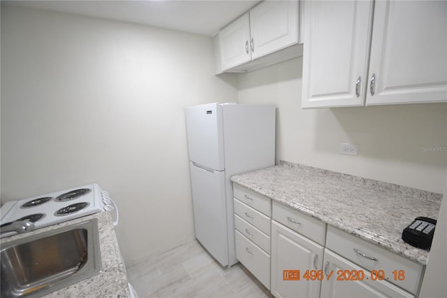 kitchen featuring range with electric stovetop, sink, white refrigerator, and white cabinetry