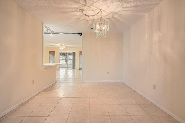 tiled spare room featuring ceiling fan with notable chandelier and a textured ceiling