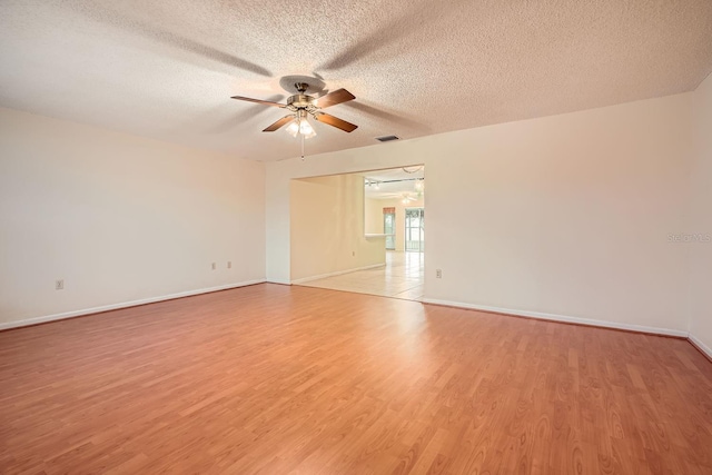 empty room featuring light wood-type flooring, ceiling fan, and a textured ceiling