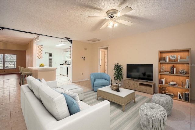 living room with ceiling fan, rail lighting, a textured ceiling, and light tile patterned floors