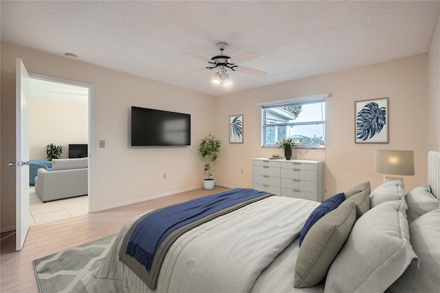 bedroom with ceiling fan, light hardwood / wood-style floors, and a textured ceiling