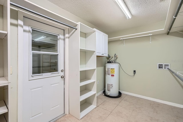 interior space with cabinets, electric dryer hookup, washer hookup, electric water heater, and light tile patterned floors