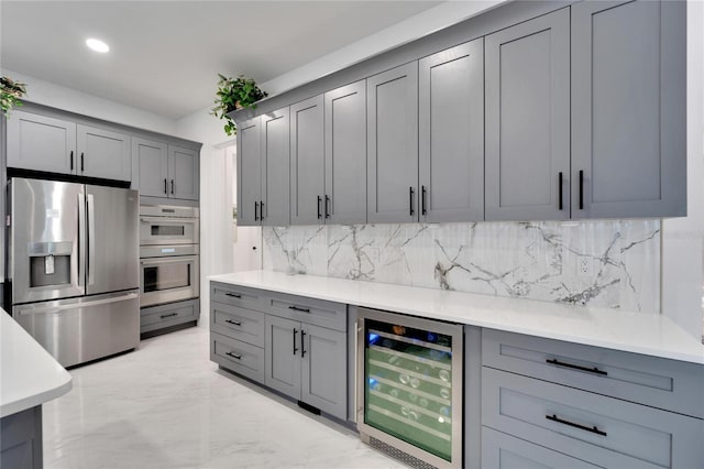 kitchen with backsplash, appliances with stainless steel finishes, beverage cooler, and gray cabinetry