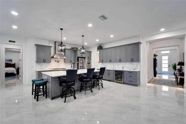 kitchen featuring appliances with stainless steel finishes, gray cabinetry, a spacious island, beverage cooler, and pendant lighting