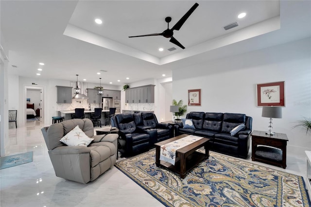 living room with ceiling fan and a tray ceiling