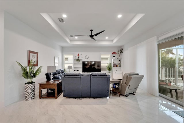 living room with ceiling fan, a healthy amount of sunlight, and a raised ceiling