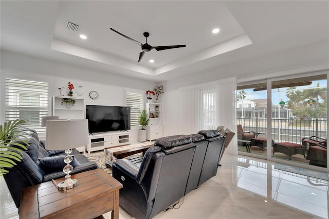 living room with a raised ceiling and ceiling fan