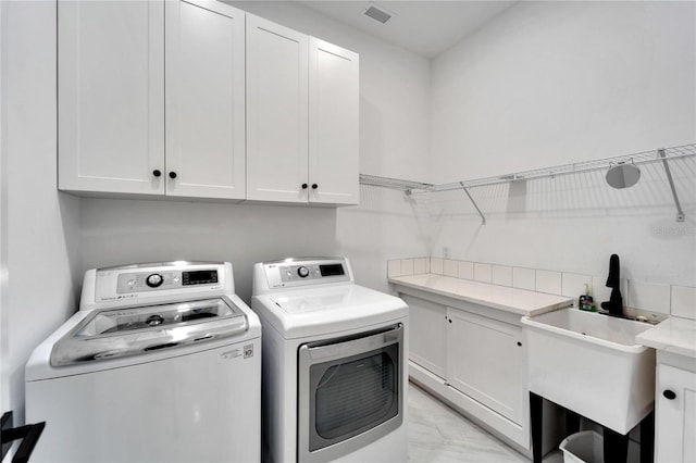 laundry room with cabinets, washer and dryer, and sink