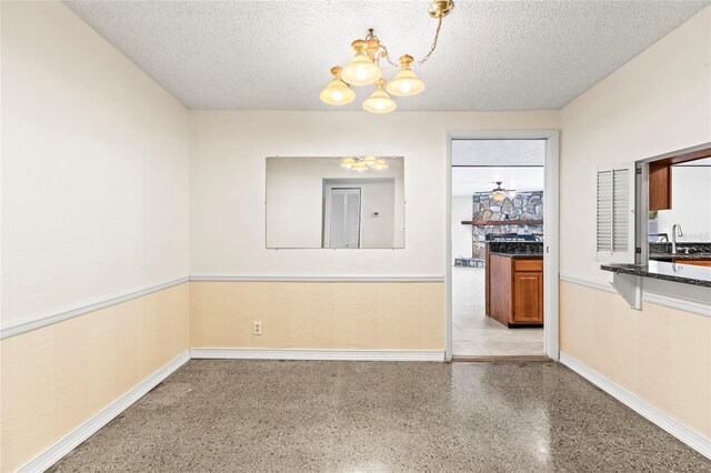 unfurnished dining area with sink, a chandelier, and a textured ceiling