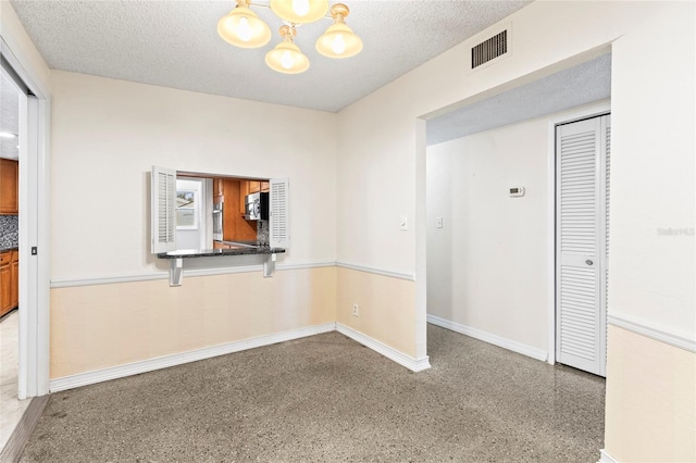 unfurnished room with an inviting chandelier and a textured ceiling