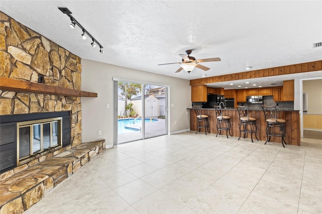 kitchen with black refrigerator, a kitchen bar, decorative backsplash, kitchen peninsula, and a textured ceiling