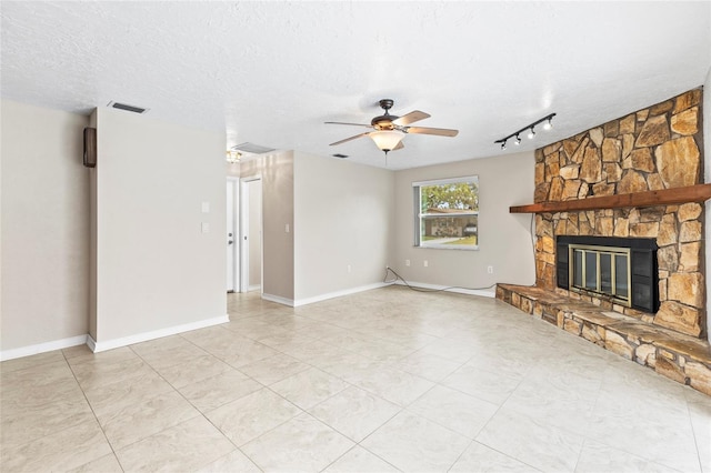 unfurnished living room featuring ceiling fan, track lighting, a fireplace, and a textured ceiling