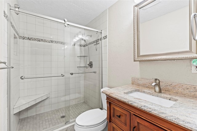 bathroom with vanity, toilet, an enclosed shower, and a textured ceiling