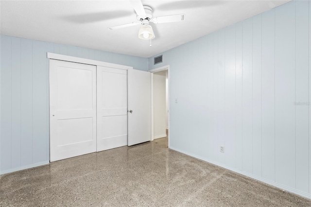 unfurnished bedroom featuring wooden walls, a closet, and ceiling fan