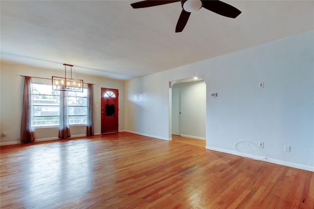 unfurnished living room with ceiling fan with notable chandelier and light hardwood / wood-style flooring