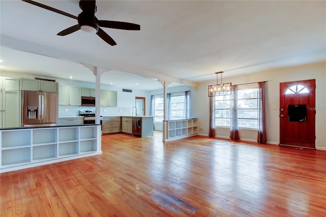 kitchen featuring appliances with stainless steel finishes, decorative light fixtures, light wood-type flooring, ceiling fan with notable chandelier, and sink