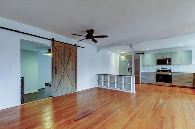 unfurnished living room featuring a barn door and light wood-type flooring