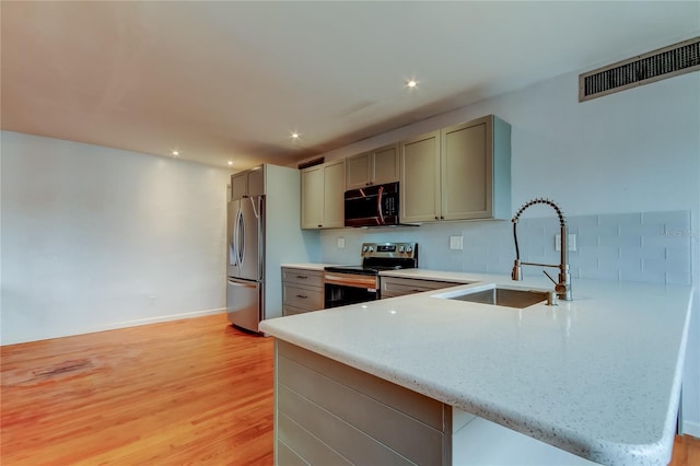 kitchen featuring stainless steel appliances, light hardwood / wood-style flooring, kitchen peninsula, and sink