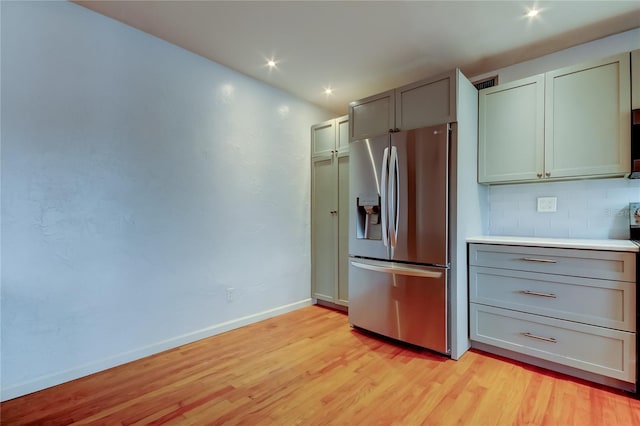 kitchen featuring stainless steel refrigerator with ice dispenser, light hardwood / wood-style floors, and tasteful backsplash